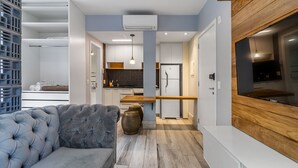 Un soggiorno moderno con un divano grigio, una parete d'accento in legno e una cucina sullo sfondo.