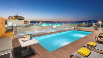 Een buitenzwembad, parasols bij het zwembad en ligstoelen