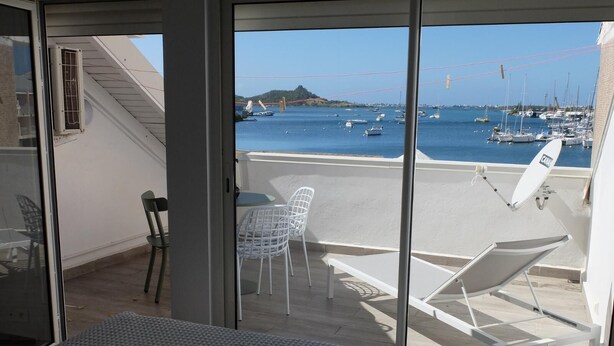 A balcony with a view of a marina, white chairs, a table, and a lounge chair. - Appartement de charme , Marina Royale, Marigot (Marigot)