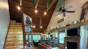 Un vaste espace de vie agrémenté d’un escalier en bois, d’un coin salon confortable et d’une cuisine située au fond de la pièce.