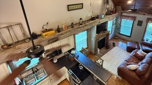 L’intérieur chaleureux d’un chalet comprend une cuisine, un coin repas et un salon. On peut y voir une décoration murale représentant une boussole et une pancarte d’accueil.
