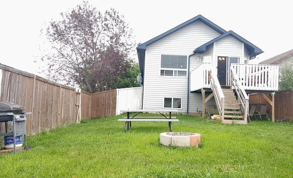 A single-story house with a deck and a small outdoor kitchen area. - 3 beds Private Cozy Patio + 4 mins Drive to restaurants, Starbucks (Grande Prairie)
