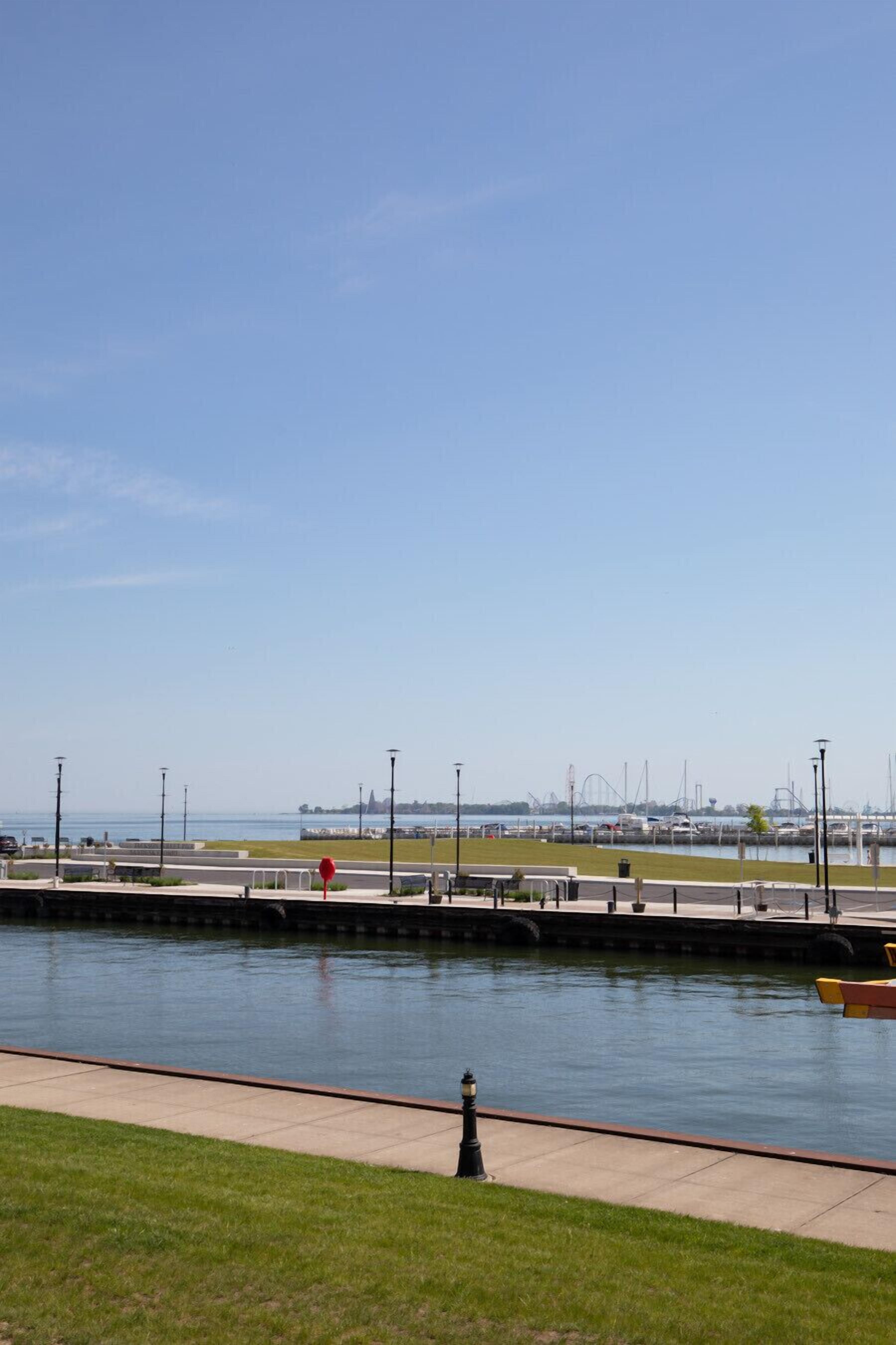 A waterfront promenade with a clear view of the marina and distant city skyline.
