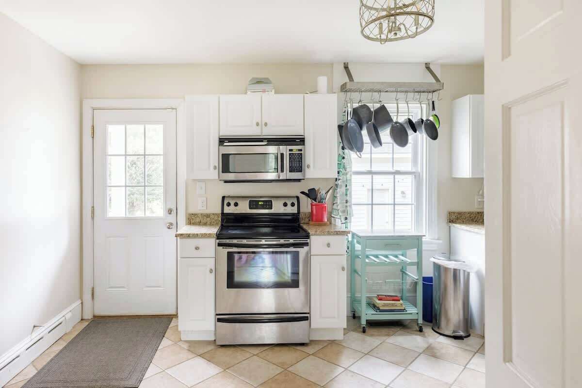 A modern kitchen with white cabinets, stainless steel appliances, and a window with a view.