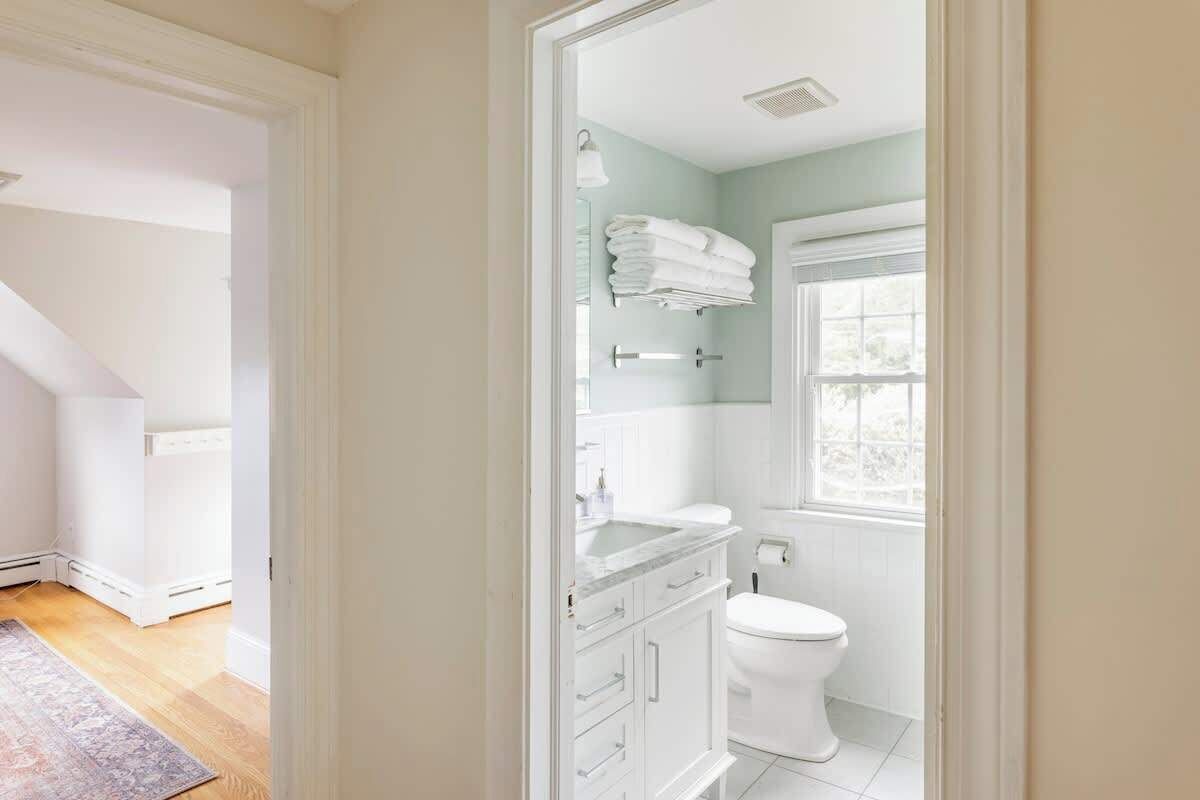 Ein modernes Badezimmer mit Toilette, Waschbecken mit Spiegel und Handtuchhalter.