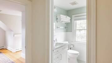 Ein modernes Badezimmer mit Toilette, Waschbecken mit Spiegel und Handtuchhalter.