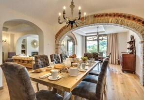 A dining area with a long wooden table, upholstered chairs, and a chandelier. - VILLA CHIANTI RUBINO (Greve in Chianti)