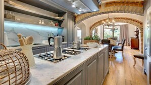 Una cocina moderna con encimera de mármol, electrodomésticos integrados y un comedor con candelabro.