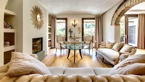 Amplia sala de estar con una mesa de centro de vidrio, sofás color beige y una chimenea.