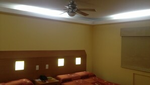 A hotel room with two beds, a ceiling fan, and a nightstand with a lamp. - Hotel Central (San Luis Potosi)
