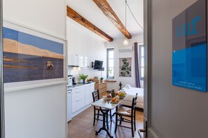 A modern kitchen with white cabinets, a dining table with chairs, and a hanging light fixture.