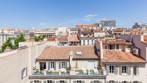 A cityscape with traditional terracotta-tiled rooftops, a mix of residential and commercial buildings, and a clear blue sky. - AZUR - LES COCONS - Studio Apartment, Sleeps 2 (Marseille)