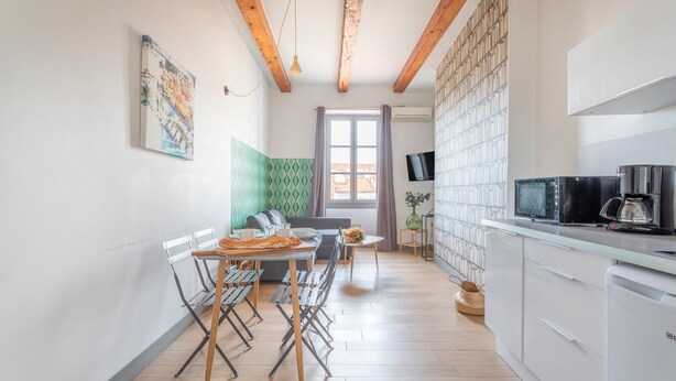 A modern kitchen with a dining area, wooden beams, a TV, and a large window. - JADE - LES COCONS - One Bedroom Apartment, Sleeps 2 (Marseille)