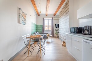 Una cucina moderna con zona pranzo, travi in legno, televisore e un'ampia finestra.