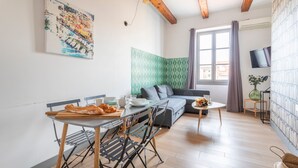 A compact living space with a dining area, a sofa, a TV, and a window with curtains. - JADE - LES COCONS - One Bedroom Apartment, Sleeps 2 (Marseille)