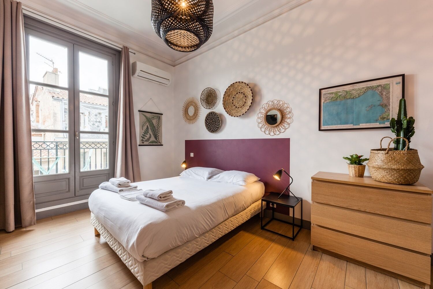 A modern bedroom with a bed, bedside table, dresser, and decorative wall art.