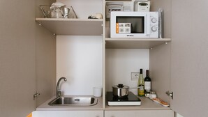 Una kitchenette compacta con un lavamanos, microondas y estufa.
