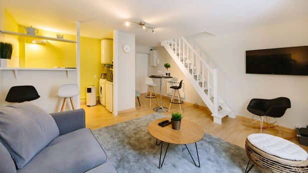 A modern living room with a sofa, coffee table, and a TV mounted on the wall.