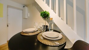 A dining table set with plates, glasses, and a water bottle, positioned near a staircase.