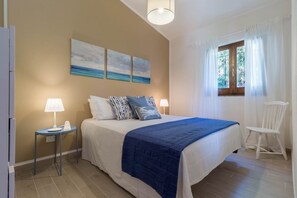 A bedroom with a bed, two bedside tables with lamps, a chair, and a window with curtains.