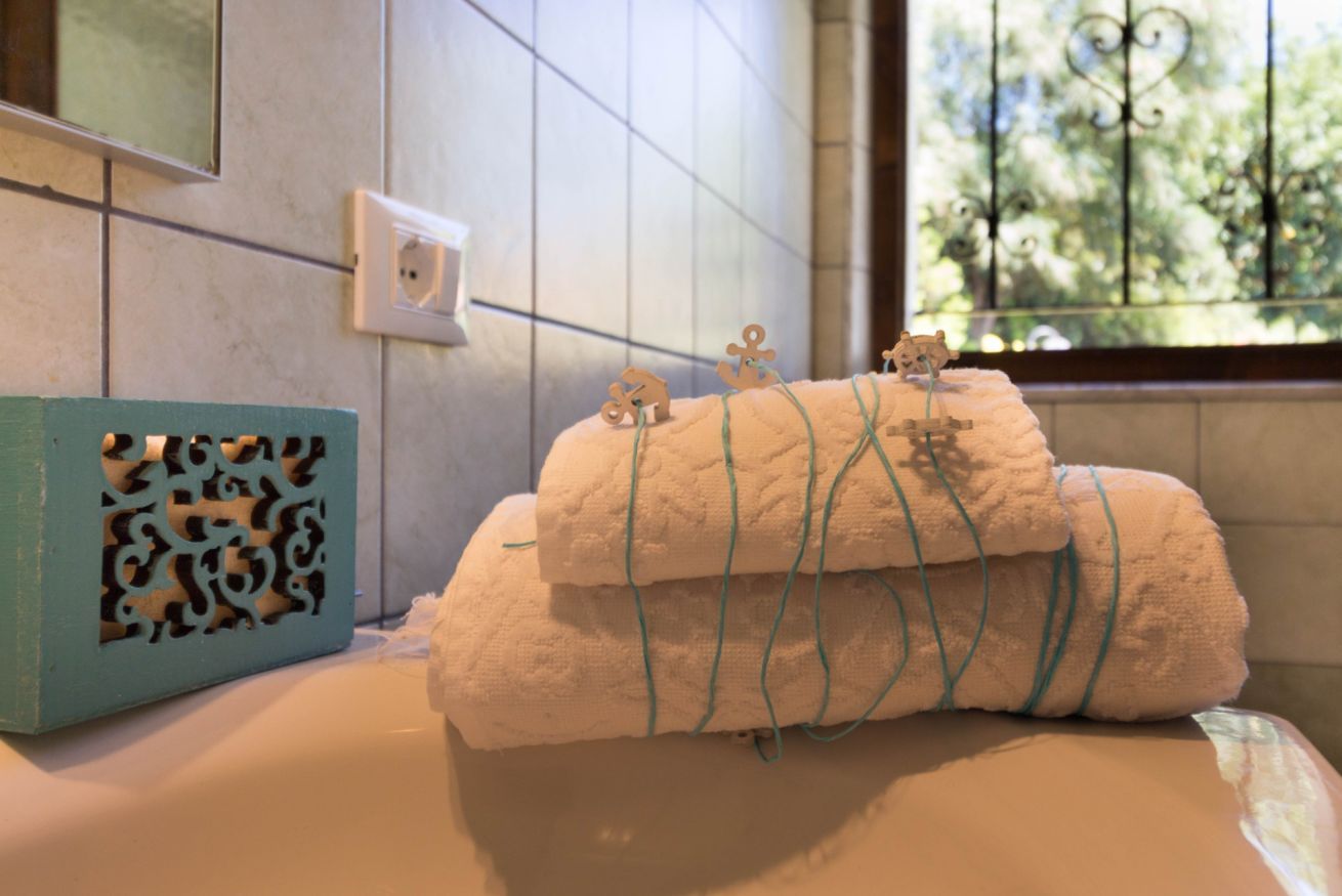 Ein Badezimmer mit einer Badewanne, einem Handtuchhalter mit Handtüchern, einer dekorativen Schachtel und einem Fenster mit Blick auf Bäume.