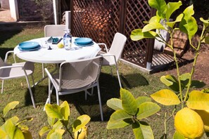 A round table with chairs, a bottle, and plates set outdoors.