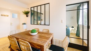 A dining area with a wooden table, wicker chairs, and a potted plant. - L'Imperti'Nantes- T3bis de Standing (Nantes)