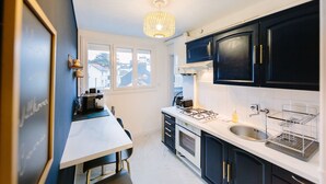 A modern kitchen with dark cabinets, a white countertop, and a gas stove. - L'Imperti'Nantes- T3bis de Standing (Nantes)
