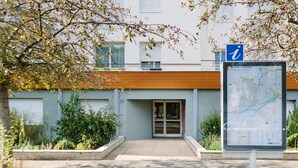 Ein Gebäudeeingang mit einer Wegweiser-Karte, einem hölzernen Vordach und einem verschlossenen Tor.