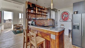 A modern kitchen with a central island, stainless steel appliances, and a 7UP logo on the wall. - LE VICTOR - Grand et lumineux T3 (Bordeaux)