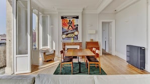 A dining area with a wooden table and chairs, a green rug, and a poster on the wall. - LE VICTOR - Grand et lumineux T3 (Bordeaux)