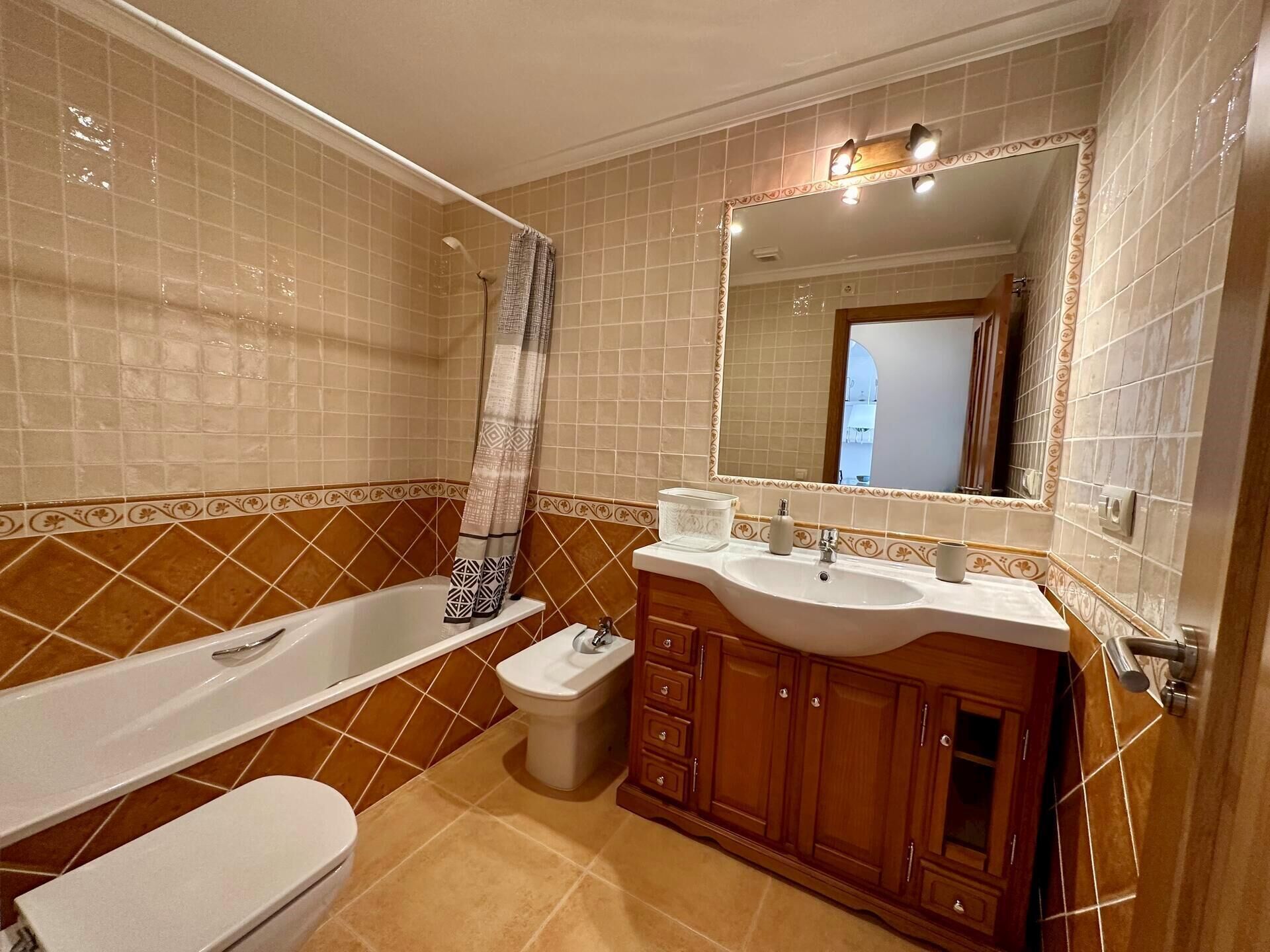 A bathroom with a bathtub, toilet, bidet, vanity with a sink, and a large mirror.