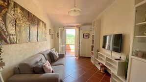A living room with a sofa, TV, and artwork on the wall. - The house in the carob trees with breathtaking views (Arcola)