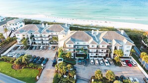 Ein Strandhotel mit mehreren Gebäuden, einem Parkplatz und Blick auf das Meer und den Strand.