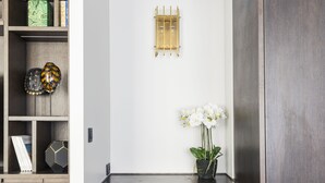 Un espacio de oficina moderno con un escritorio de madera oscura, una silla gris y una orquídea blanca.