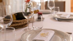 Une table à manger dressée avec des assiettes, des verres et une serviette pliée.