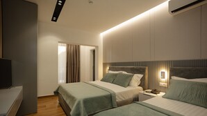 Une chambre d’hôtel moderne avec deux lits, un bureau et une télévision.