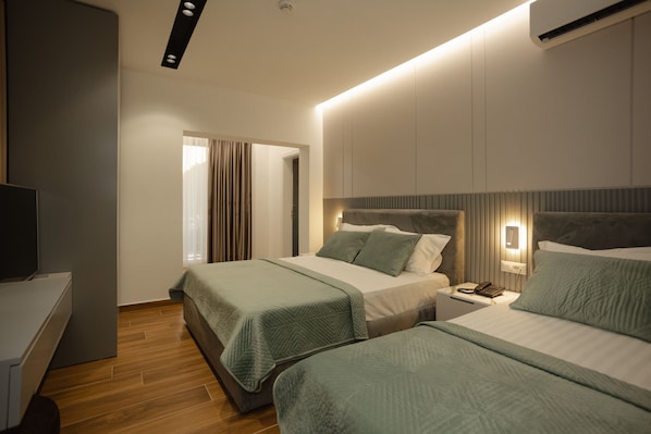 Una habitación de hotel moderna con dos camas, un escritorio y un televisor.