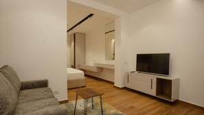 Un salon moderne avec un canapé, un téléviseur posé sur un meuble et une petite table.