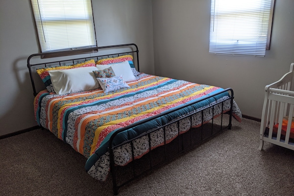 Master bedroom with a platform style king bed and a crib. Attached full bathroom