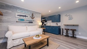 A modern living room with a white sofa, wooden coffee table, and nautical-themed wall art. - Lakeside Serenity: One-Bedroom Villa (Bridgman)