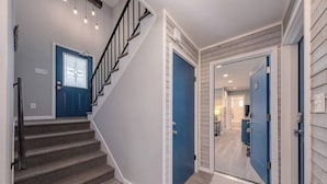 A staircase leading to a landing with a blue door, a second blue door, and a hallway with a light-colored floor. - Lakeside Serenity: One-Bedroom Villa (Bridgman)