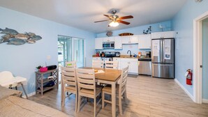 A modern kitchen with white cabinets, stainless steel appliances, and a wooden dining table. - WATERFRONT!! Home w/ 37.5-ft dock, Cabana Club Membership!!! (Key Colony Beach)