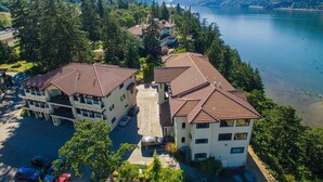 A two-story building with a tiled roof, surrounded by trees and a lake. - Luxurious Condominium 1 - 3 bedrooms available (Hood River)