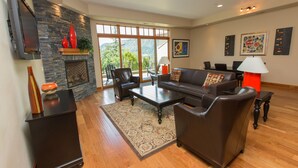 A spacious living room with a fireplace, leather furniture, and large windows offering a view of the outdoors. - Luxurious Condominium 1 - 3 bedrooms available (Hood River)