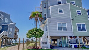 A multi-story beachfront building with a staircase leading to the upper floors, a palm tree in front, and a beach view. - 2284-B New River Inlet Road- Direct Oceanfront 3 bedroom- Adjoining Side is Available for Rent- 2... (North Topsail Beach)