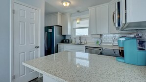 A kitchen with white cabinets, a stainless steel refrigerator, a microwave, and a teal coffee maker. - 2284-B New River Inlet Road- Direct Oceanfront 3 bedroom- Adjoining Side is Available for Rent- 2... (North Topsail Beach)