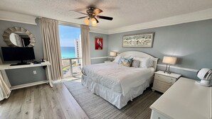 Un dormitorio con cama, escritorio, ordenador y vistas al océano.