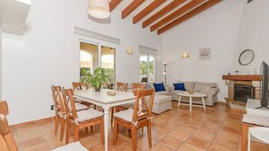 A spacious living area with a dining table, chairs, a sofa, and a fireplace. - Villa Astur ☀☀Charming Villa with private pool and garden (Binibequer)