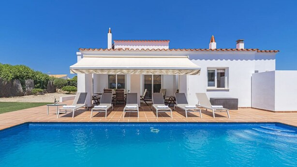 A modern house with a swimming pool, white exterior, and a covered patio area with lounge chairs. - Villa Astur ☀☀Charming Villa with private pool and garden (Binibequer)